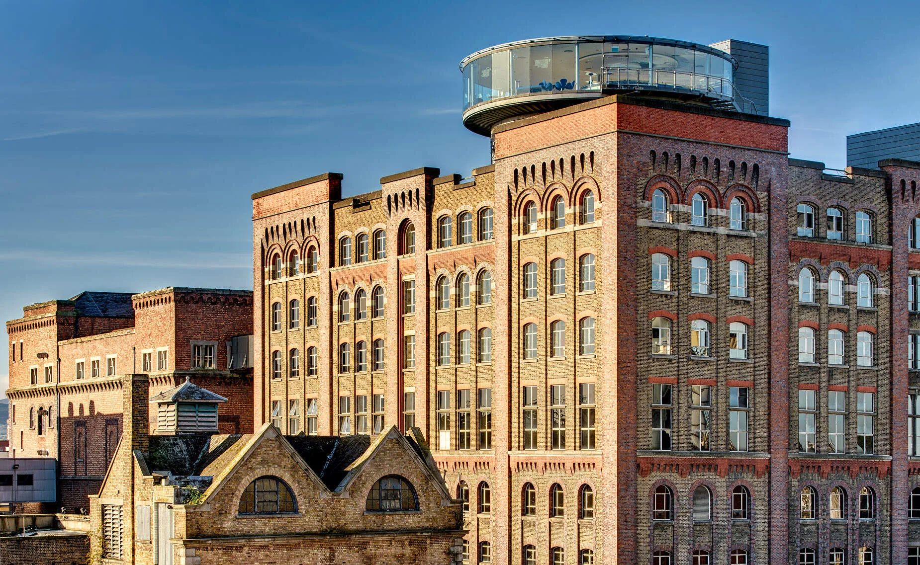 Guinness Storehouse exterior with its distinctive pint glass architecture set against Dublin cityscape, the Gravity Bar visible at the top