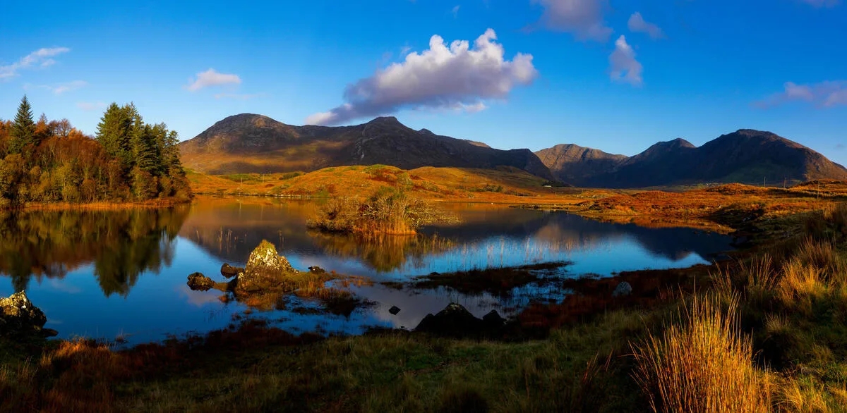 Tranquil Ballynahinch Lake reflecting surrounding mountains at the western end in Connemara, County Galway