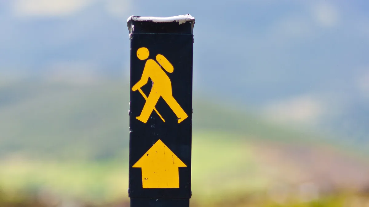 Yellow walking-man waymarker on the Wicklow Way, the sign walkers follow on a self-guided walking holiday in Ireland