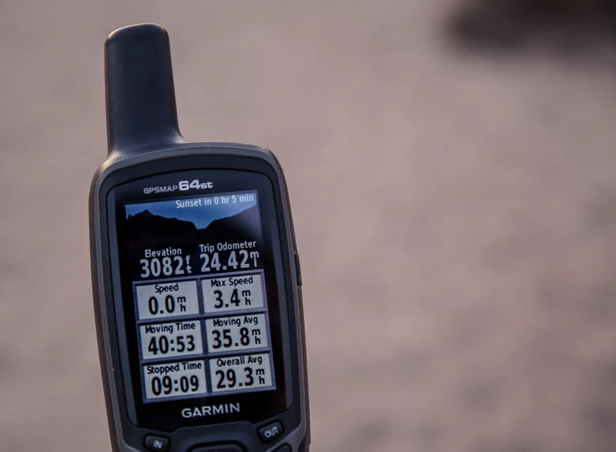 Close-up of a Garmin GPSMAP handheld GPS for hiking showing trip data on screen